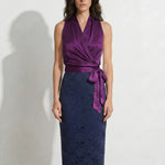 A style comparison of two professional office outfits: the left showing a sleeveless color-block lace dress with a white 3D flower bodice, and the right featuring a rich purple satin wrap halter top paired with the same navy blue lace pencil skirt for a sophisticated corporate look.