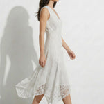 A professional woman modeling an elegant white lace sleeveless dress, featuring a sophisticated V-neckline, a tailored fit-and-flare silhouette, and an intricate hollow-out eyelet texture with a delicate lace trim hem.