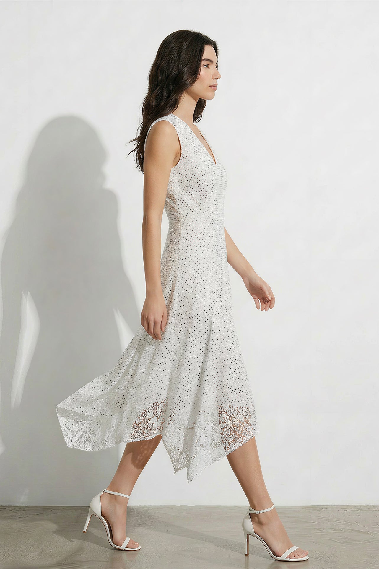 A professional woman modeling an elegant white lace sleeveless dress, featuring a sophisticated V-neckline, a tailored fit-and-flare silhouette, and an intricate hollow-out eyelet texture with a delicate lace trim hem.