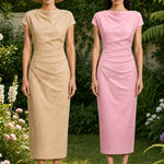 A professional woman modeling an elegant pastel pink satin midi dress, featuring a sophisticated cowl neckline, delicate cap sleeves, and slimming asymmetric ruched drapes across the waist for a quiet luxury look.