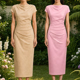 A professional woman modeling an elegant pastel pink satin midi dress, featuring a sophisticated cowl neckline, delicate cap sleeves, and slimming asymmetric ruched drapes across the waist for a quiet luxury look.