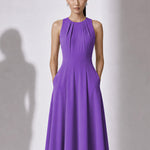 A style comparison of two elegant tailored midi dresses with a flowing high-low hem; the left showcasing a sophisticated light grey dress with a structured collared capelet sleeve, and the right featuring a vibrant purple sleeveless dress with refined pleated neckline and side pockets.