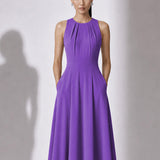 A style comparison of two elegant tailored midi dresses with a flowing high-low hem; the left showcasing a sophisticated light grey dress with a structured collared capelet sleeve, and the right featuring a vibrant purple sleeveless dress with refined pleated neckline and side pockets.