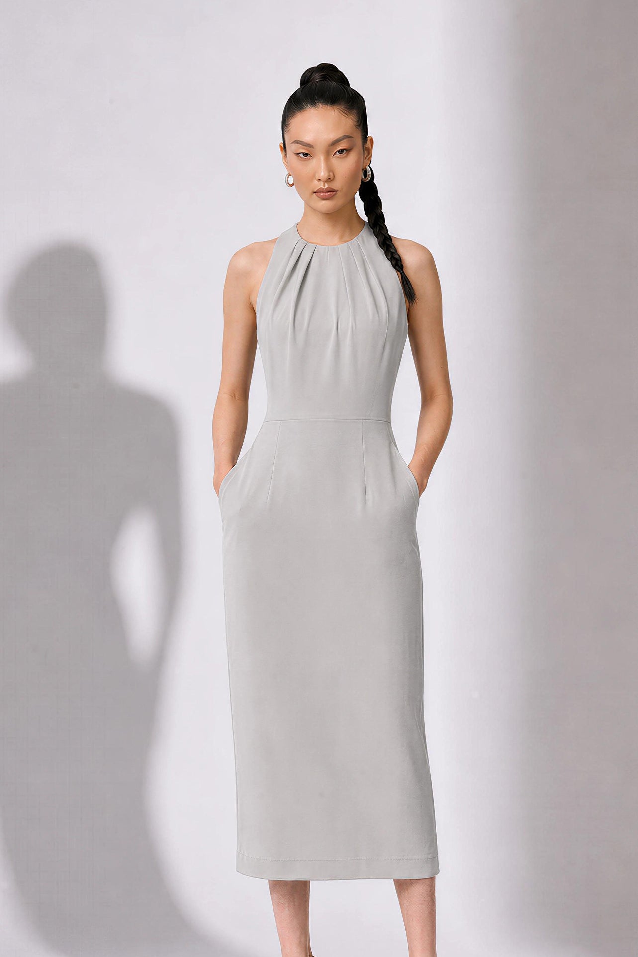 A style comparison of two elegant tailored office sheath midi dresses; the left showcasing a structured vibrant purple dress with a collared capelet sleeve design, and the right featuring a minimalist light grey sleeveless dress with subtle pleated neckline and side pockets.