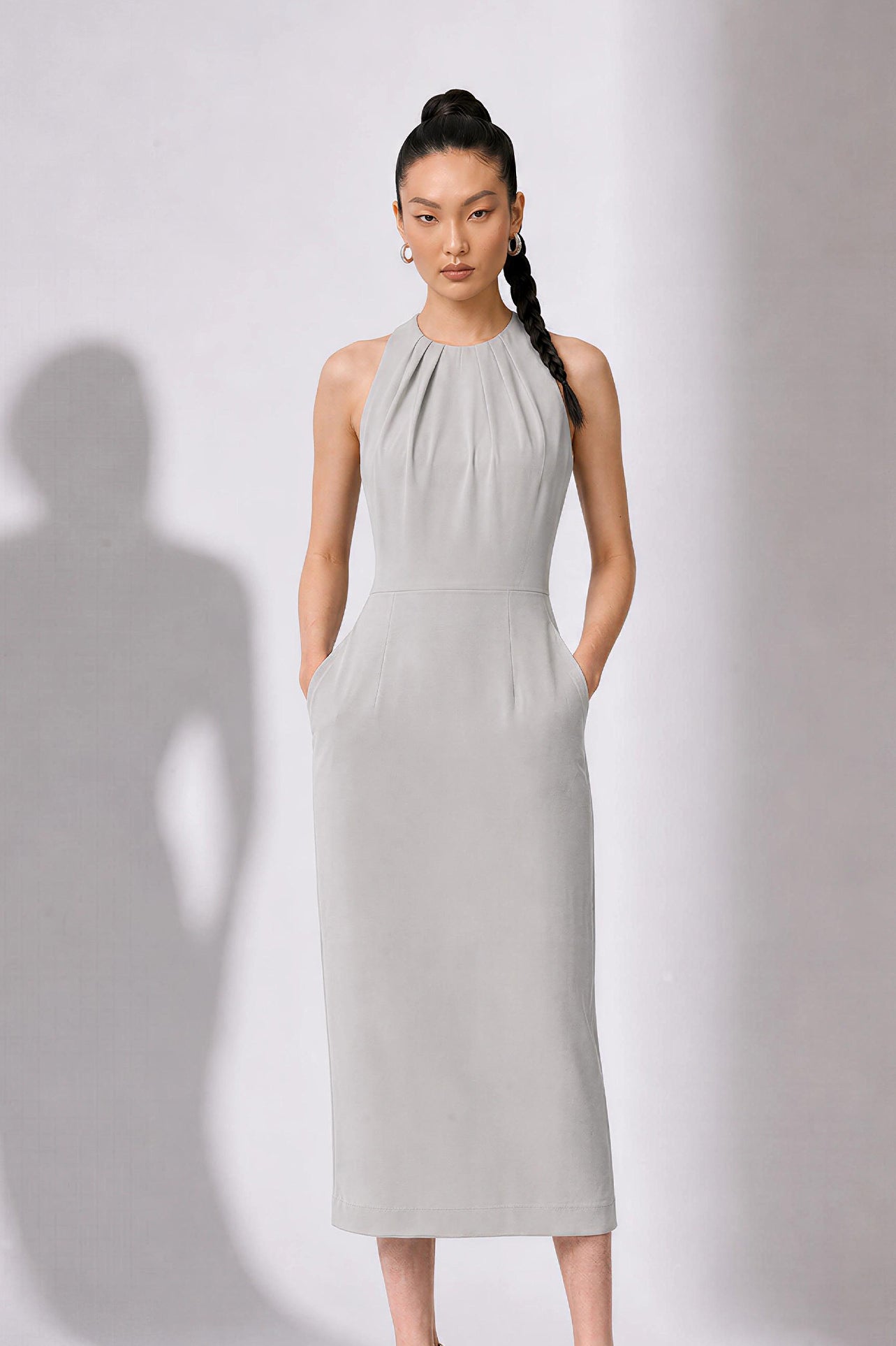 A style comparison of two elegant tailored office sheath midi dresses; the left showcasing a structured vibrant purple dress with a collared capelet sleeve design, and the right featuring a minimalist light grey sleeveless dress with subtle pleated neckline and side pockets.