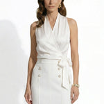 A professional woman modeling elegant satin halter wrap tops in crisp white and deep purple, featuring a sophisticated side bow tie and paired with white high-waisted trousers and a button-front skirt.