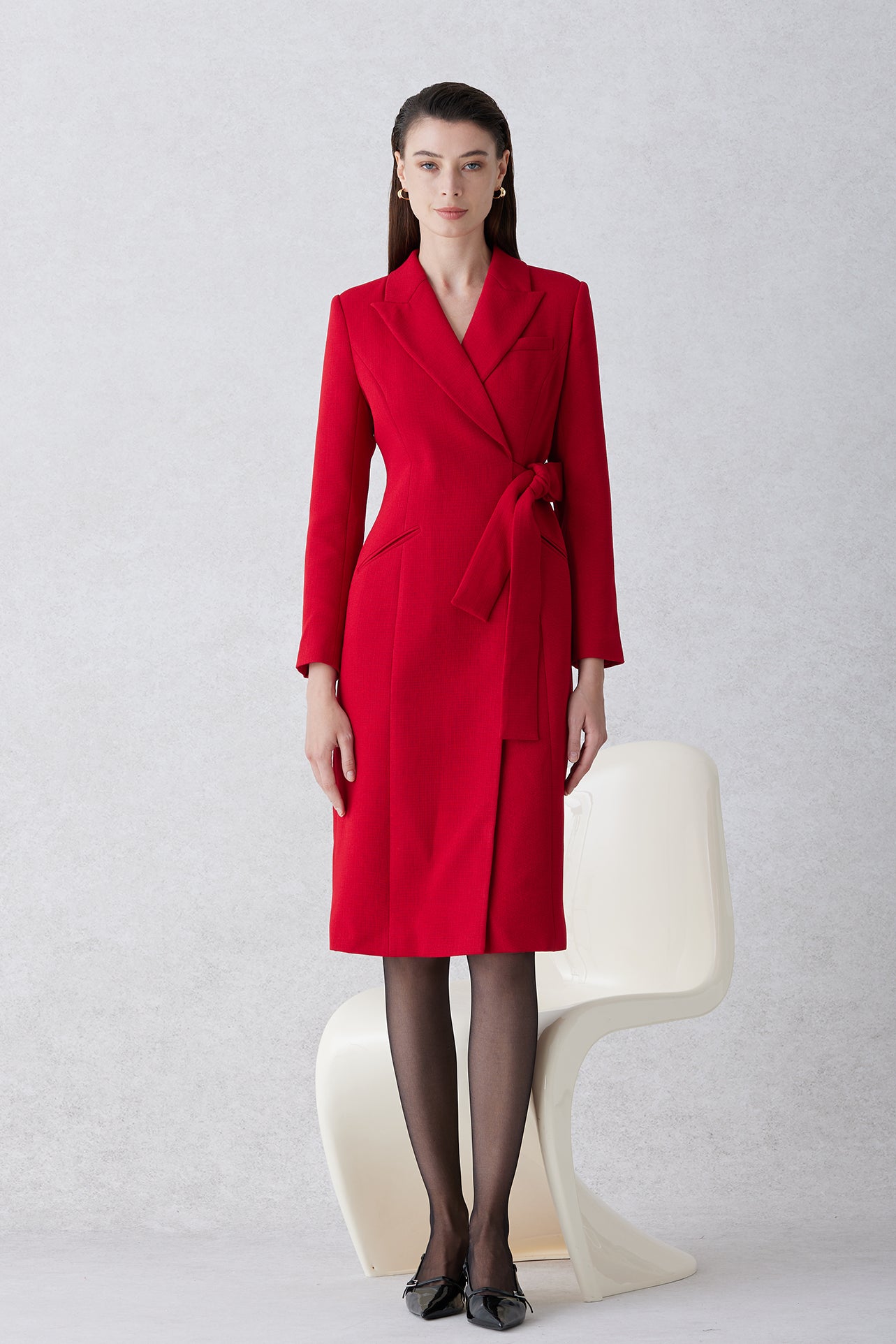 A sophisticated woman walking in London wearing an elegant vibrant red wrap coat dress, featuring a tie-waist belt and notched lapels for a polished executive street style look.