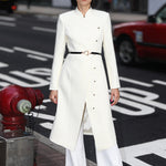 A professional woman smiling in a stunning festive red coat dress, featuring a stand-up mandarin collar with a large 3d rose ornament and an elegant side-button closure, perfect for a Christmas or holiday formal event.