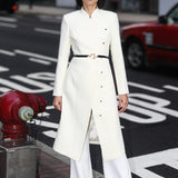 A professional woman smiling in a stunning festive red coat dress, featuring a stand-up mandarin collar with a large 3d rose ornament and an elegant side-button closure, perfect for a Christmas or holiday formal event.