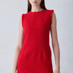 A professional woman wearing a sophisticated vibrant red tweed sleeveless mini dress, featuring a classic round neck, elegant frayed edges, and a slimming black waist belt for a chic holiday or office look.