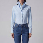 A professional woman wearing a classic crisp white long-sleeve slim-fit blouse with a sharp point collar, styled with a navy blue pencil skirt for a polished executive office look.