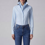 A professional woman wearing a classic crisp white long-sleeve slim-fit blouse with a sharp point collar, styled with a navy blue pencil skirt for a polished executive office look.