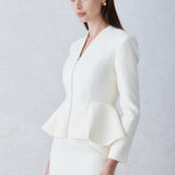 A professional woman wearing a sophisticated cream tweed skirt suit, featuring a tailored jacket with a modern front zipper and an elegant stand collar for a polished executive office look.