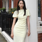 A professional woman wearing a sophisticated pale yellow short-sleeve midi dress, featuring elegant puff sleeves and a slimming ruched waistline for a polished and fresh summer office look.