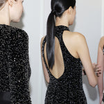 A stunning woman wearing a sophisticated black sequin halter midi dress, featuring a traditional mandarin collar and a shimmering bodycon silhouette, perfect for a modern oriental-inspired evening party look.