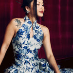 A stunning modern oriental gala dress featuring a classic blue and white porcelain floral print, an elegant halter neck with keyhole detail, and a voluminous A-line full skirt for a sophisticated formal look.