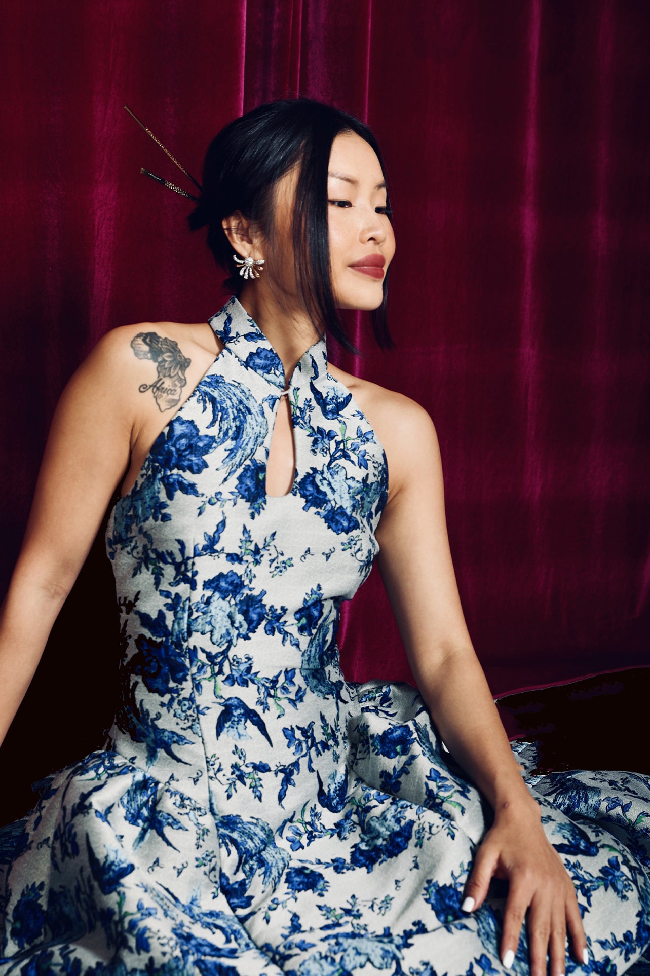 A stunning modern oriental gala dress featuring a classic blue and white porcelain floral print, an elegant halter neck with keyhole detail, and a voluminous A-line full skirt for a sophisticated formal look.