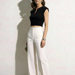 A professional woman modeling an elegant black and white color-block sheath dress, featuring a sleeveless black bodice with metallic hardware and a tailored white pencil skirt for a sophisticated executive look.