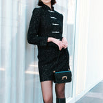 A detailed shot of a woman modeling a sophisticated black woven tweed mini skirt adorned with subtle shimmering crystals, tailored in a sleek high-waisted pencil cut.
