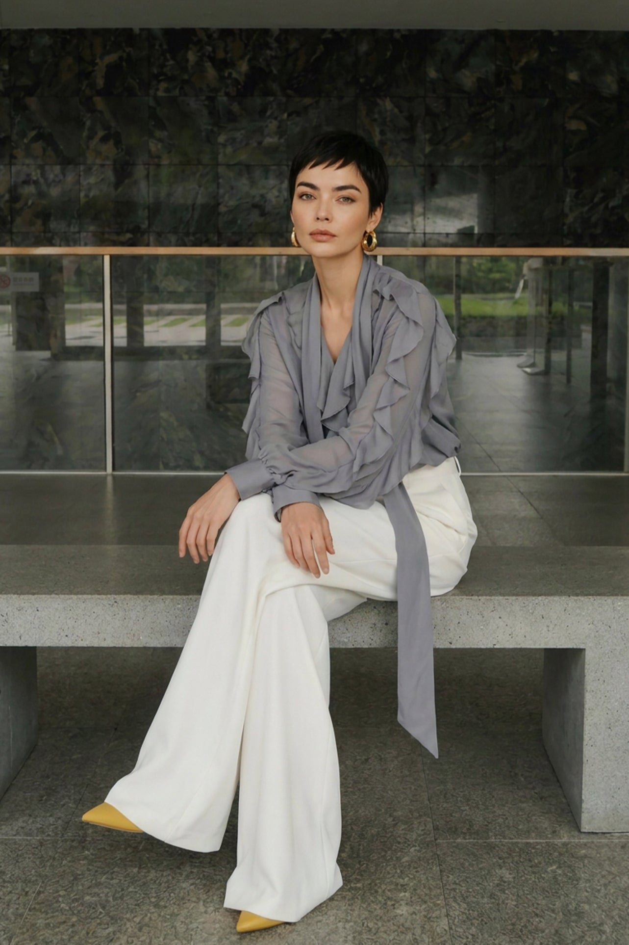 A style comparison of two professional office outfits featuring high-waisted white wide-leg trousers; the left paired with a vibrant purple ruffled V-neck chiffon blouse, and the right styled with a sophisticated grey long-sleeve blouse with a flowing tie-neck scarf.