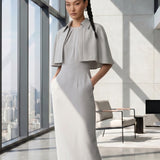 A style comparison of two elegant tailored office sheath midi dresses; the left showcasing a structured vibrant purple dress with a collared capelet sleeve design, and the right featuring a minimalist light grey sleeveless dress with subtle pleated neckline and side pockets.