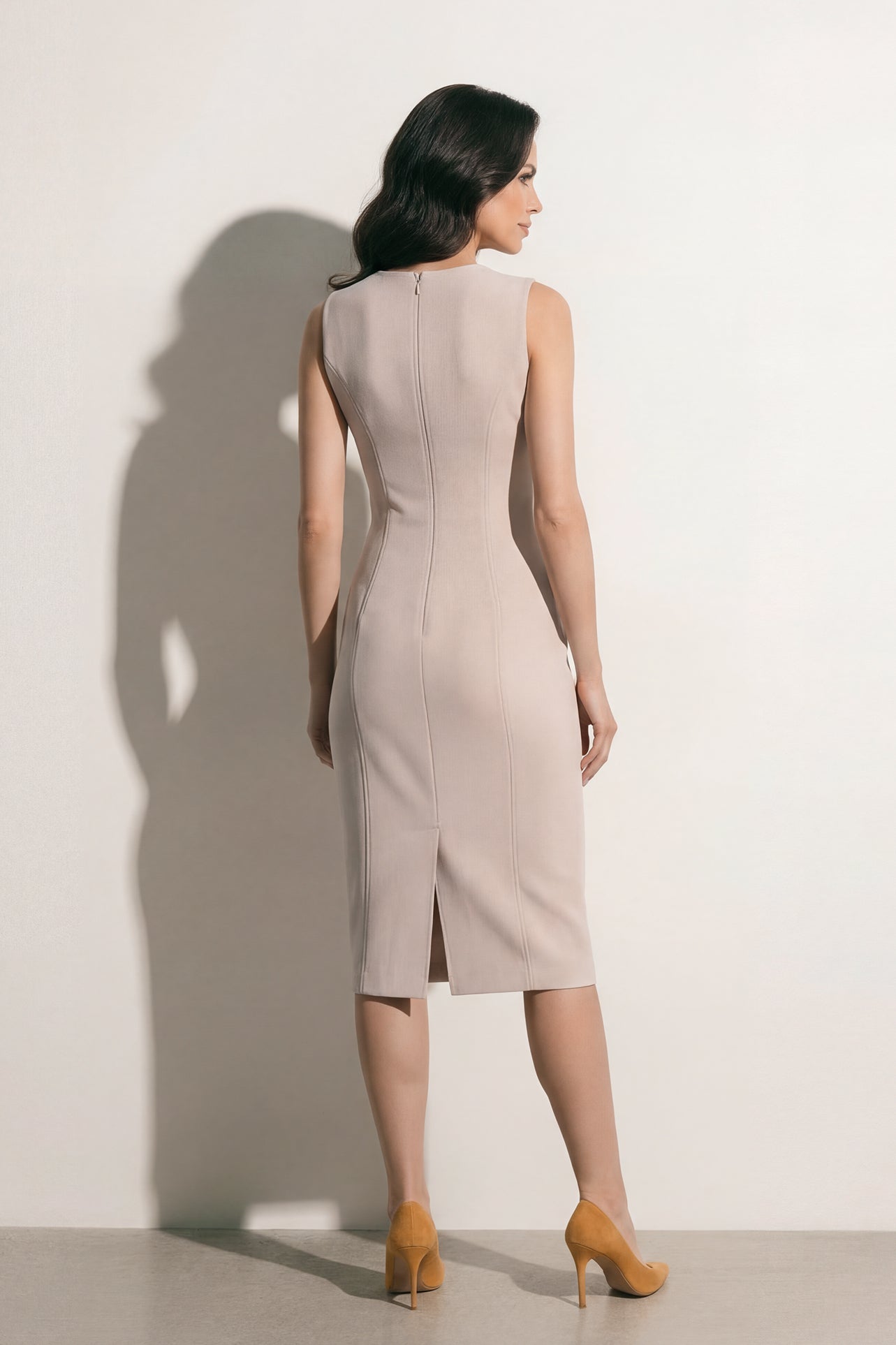 A professional woman modeling an elegant mustard yellow sleeveless sheath dress, featuring a sophisticated crew neckline and a tailored slim fit with princess seams for a polished executive look.