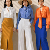 A style comparison of two elegant tailored midi pencil skirts with a sharp front slit; the left showcasing a vibrant royal blue high-waisted skirt paired with a striped shirt, and the right featuring a rich mustard yellow version paired with a bright orange blouse.