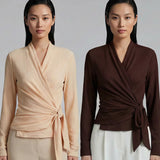 Two models presenting versatile textured wrap tops in cream and dark chocolate, featuring a slimming V-neck and elegant side-tie waist, styled with a tan pencil skirt and white high-waisted trousers.