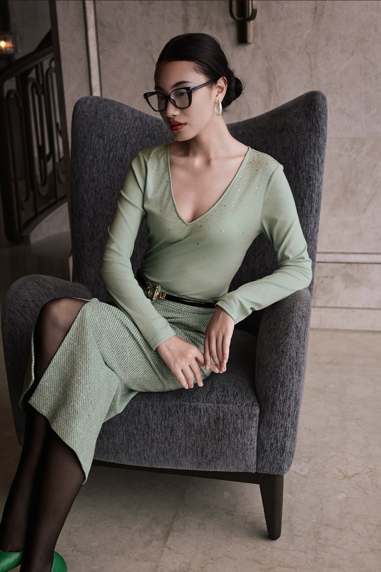 A woman wearing an elegant high-waisted mint green textured pencil midi skirt featuring a clean front waistband and a sophisticated front center slit for a refined corporate chic look.