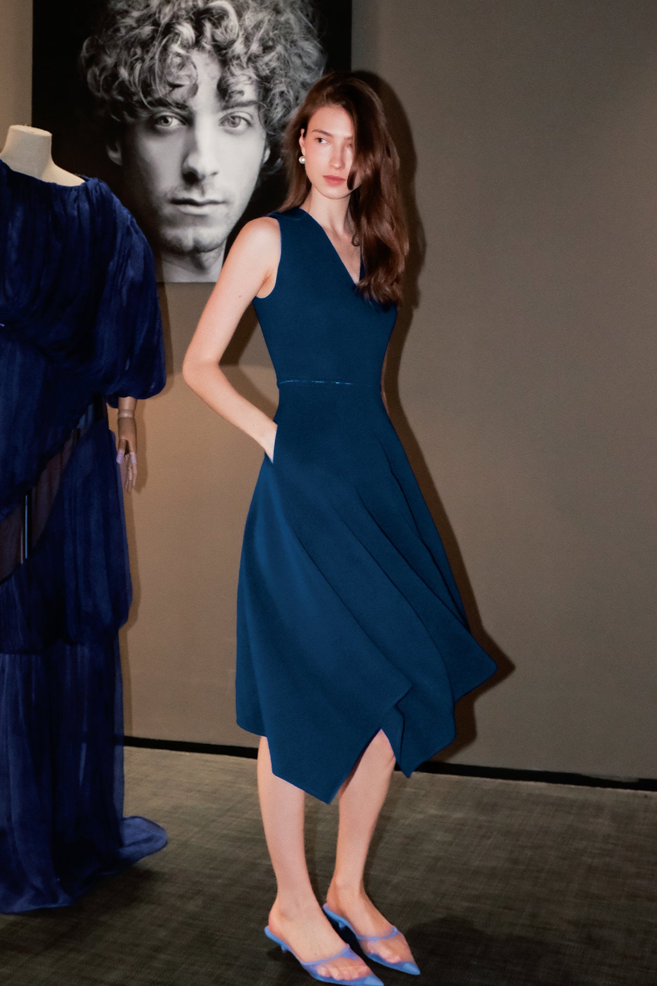 A professional woman modeling an elegant royal blue sleeveless V-neck dress, featuring a tailored fit-and-flare silhouette and a flowing midi A-line skirt for a sophisticated office or social look.