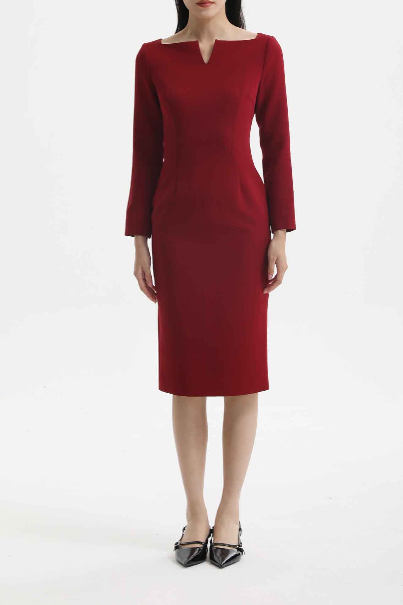 A professional woman wearing a sophisticated black long-sleeve midi dress, featuring a unique notched square neckline and a tailored slim-fit pencil silhouette for a polished executive office look.