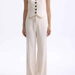 A professional woman wearing sophisticated cream pinstripe high-waisted wide-leg trousers, featuring a tailored loose-fit silhouette and styled with a pearl handbag for an elegant old money office look.