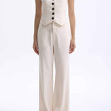 A professional woman wearing sophisticated cream pinstripe high-waisted wide-leg trousers, featuring a tailored loose-fit silhouette and styled with a pearl handbag for an elegant old money office look.