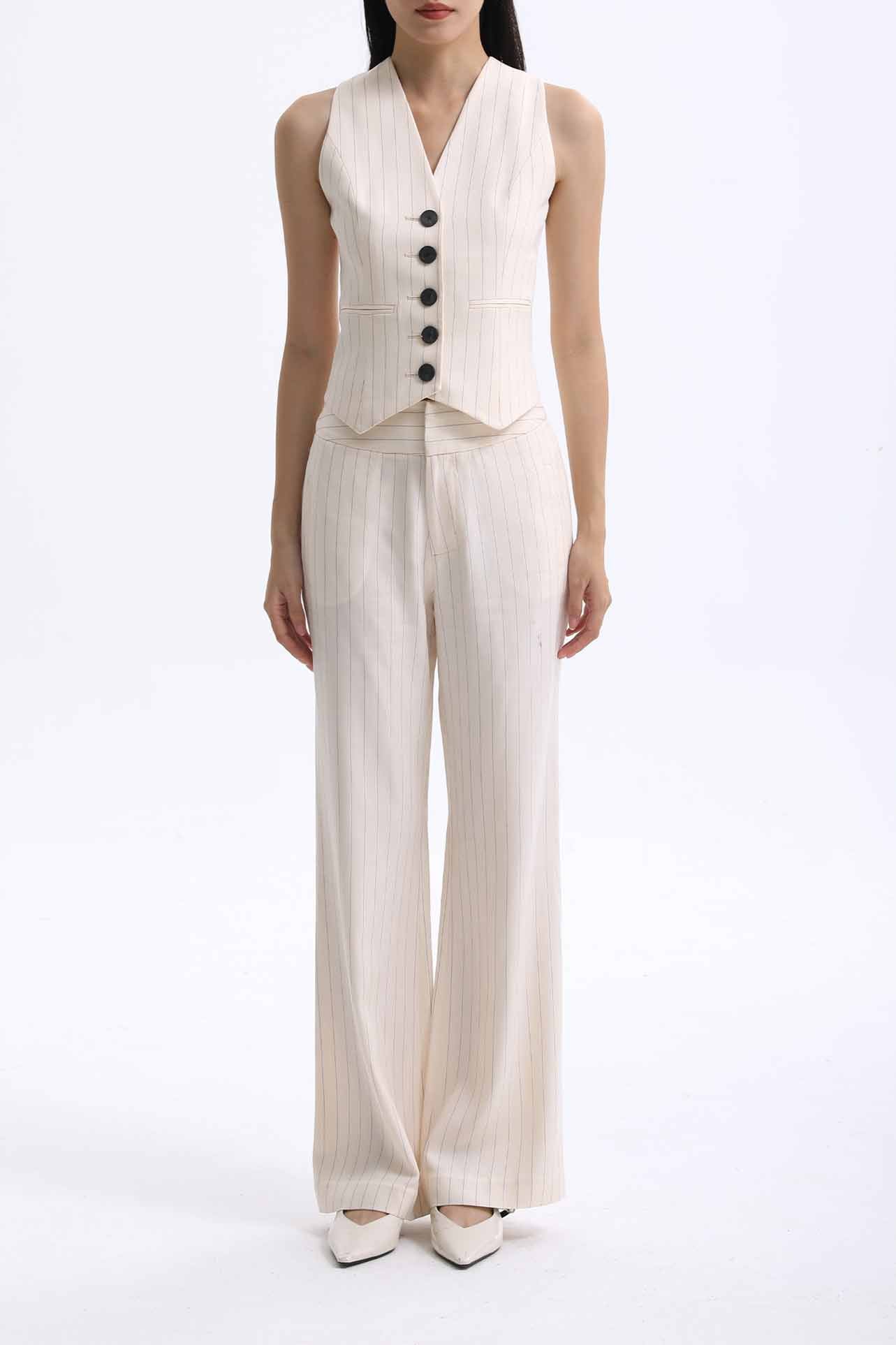 A professional woman wearing sophisticated cream pinstripe high-waisted wide-leg trousers, featuring a tailored loose-fit silhouette and styled with a pearl handbag for an elegant old money office look.