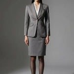 A professional woman wearing a sophisticated grey slim-fit blazer with a single gold button, featuring a tailored waist and notched lapels for an elegant executive office look.