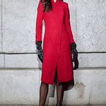 A professional woman smiling in a stunning festive red coat dress, featuring a stand-up mandarin collar with a large 3d rose ornament and an elegant side-button closure, perfect for a Christmas or holiday formal event.
