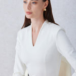 A professional woman wearing a sophisticated solid white long-sleeve sheath dress, featuring an elegant V-neckline and a slim black belt with a gold buckle for a polished executive office look.