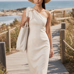 A style comparison of two elegant one-shoulder midi dresses; the left showcasing a sophisticated beige tailored sheath dress with a large tie-bow shoulder strap, and the right featuring the same design in timeless minimalist black.