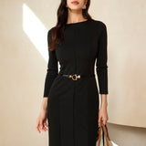 A professional woman wearing a sophisticated black long-sleeve sheath dress, featuring a classic crew neckline and a slim black belt with a gold buckle for a polished executive office look.