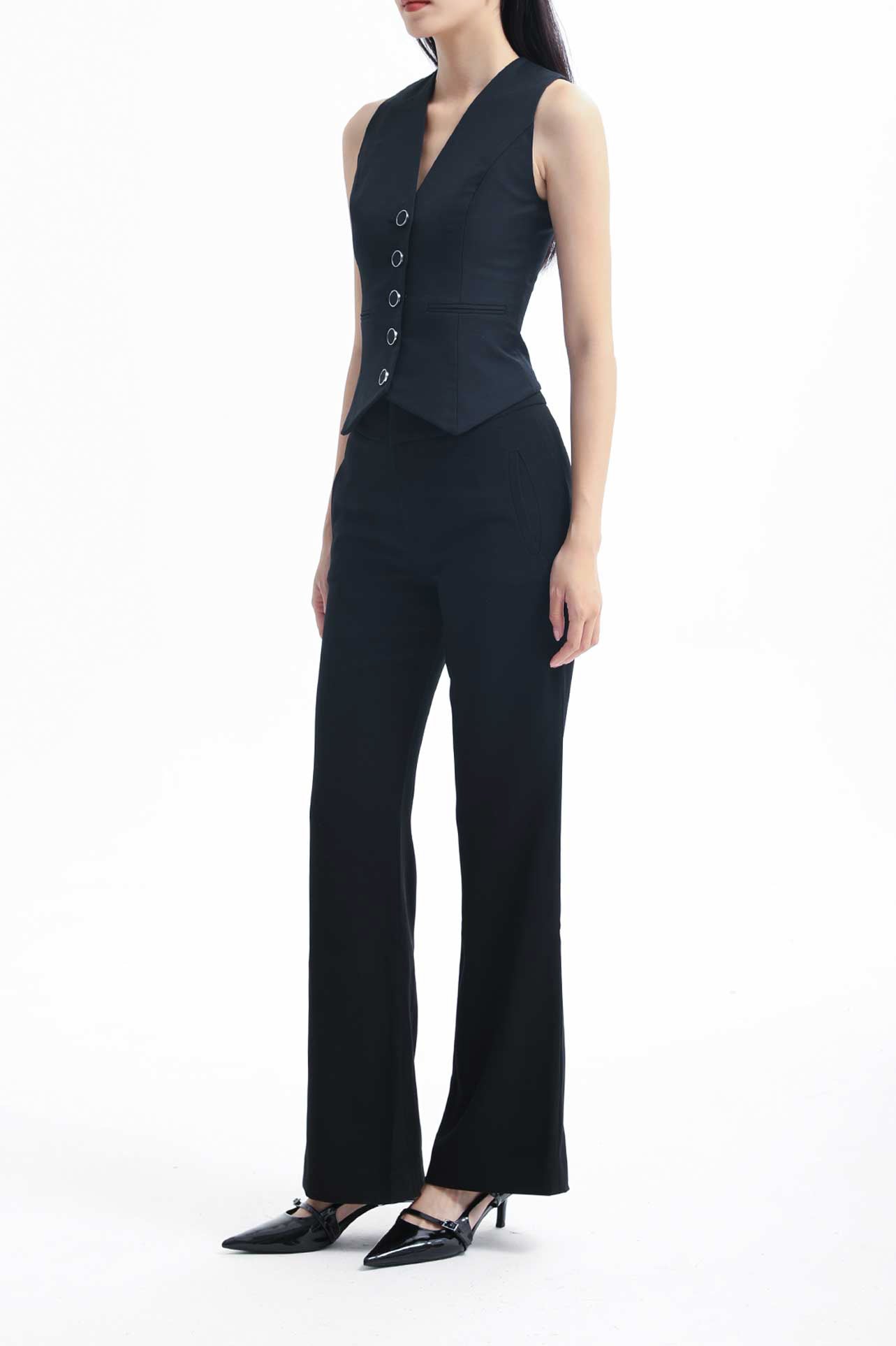 A professional woman wearing sophisticated black high-waisted straight-leg trousers, featuring a tailored silhouette with creased front details for a polished executive office look.