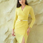 A professional woman wearing a sophisticated dark plum long-sleeve wrap dress, featuring a deep V-neckline, flattering ruched side detailing, and an elegant side slit for a formal evening or executive look.