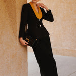 A professional Asian woman wearing glasses and an elegant black tailored blazer featuring a striking mustard yellow contrast shawl lapel, statement front button, and buttoned cuffs for a sophisticated intellectual corporate look.