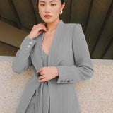 A beautiful professional model wearing an elegant grey pinstripe collarless blazer featuring a distinctive tie-front knot at the waist, styled with a crisp white collared shirt underneath for a modern corporate chic look.