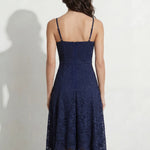 A professional woman modeling an elegant navy blue lace midi dress, featuring delicate V-neck spaghetti straps, a tailored fit-and-flare silhouette, and a beautiful flowing asymmetric handkerchief lace trim hem.