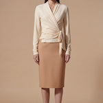 Two models presenting versatile textured wrap tops in cream and dark chocolate, featuring a slimming V-neck and elegant side-tie waist, styled with a tan pencil skirt and white high-waisted trousers.