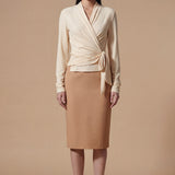 Two models presenting versatile textured wrap tops in cream and dark chocolate, featuring a slimming V-neck and elegant side-tie waist, styled with a tan pencil skirt and white high-waisted trousers.