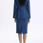A professional woman wearing a sophisticated royal blue tailored skirt suit, featuring a slim-fit single-button blazer with structured shoulders and a matching midi pencil skirt for a powerful executive office look.