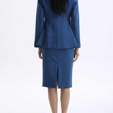 A professional woman wearing a sophisticated royal blue tailored skirt suit, featuring a slim-fit single-button blazer with structured shoulders and a matching midi pencil skirt for a powerful executive office look.