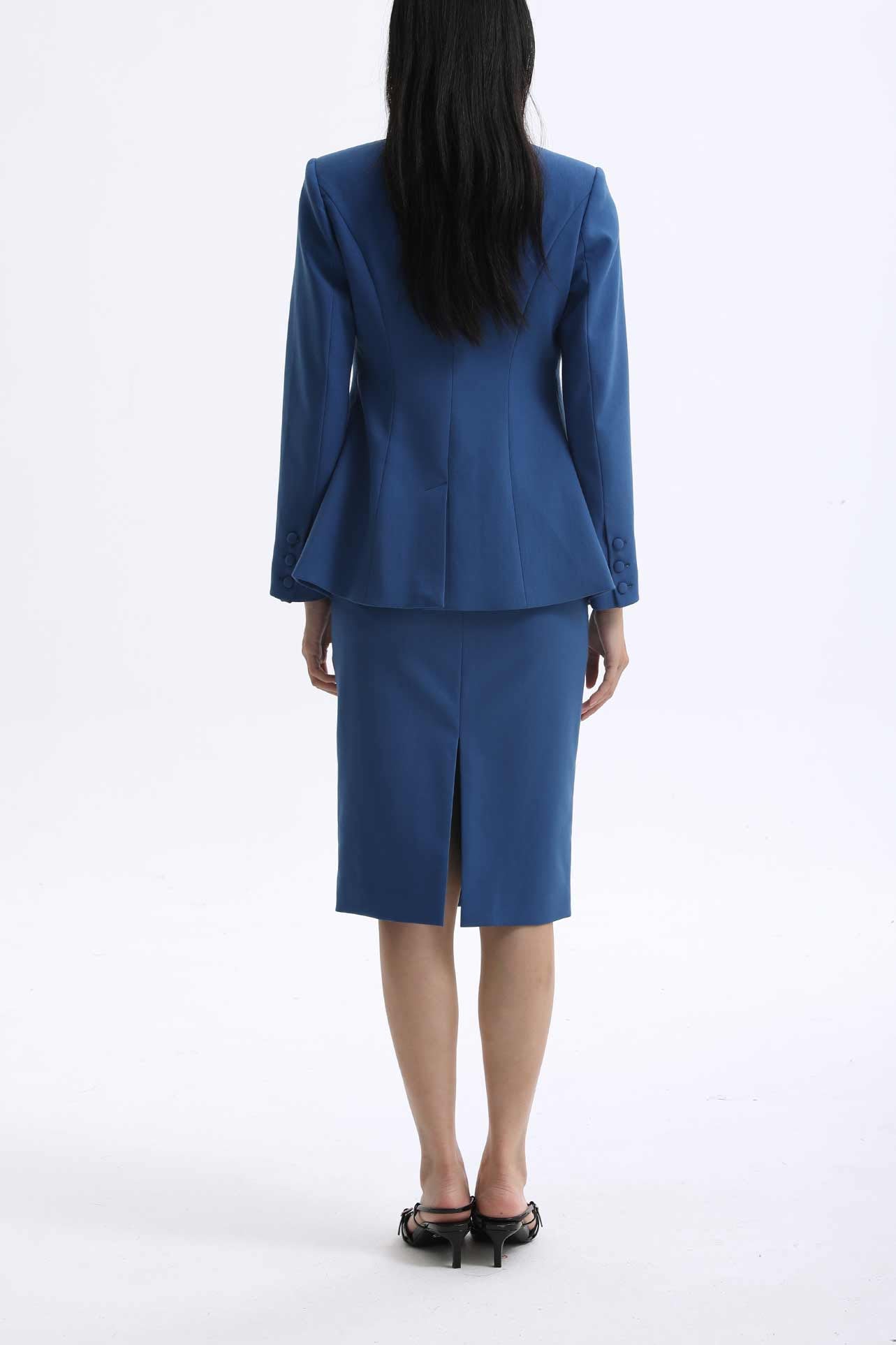 A professional woman wearing a sophisticated royal blue tailored skirt suit, featuring a slim-fit single-button blazer with structured shoulders and a matching midi pencil skirt for a powerful executive office look.