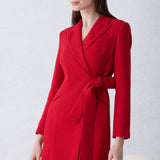 A sophisticated woman walking in London wearing an elegant vibrant red wrap coat dress, featuring a tie-waist belt and notched lapels for a polished executive street style look.